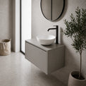 Modern bathroom with a floating vanity, round mirror, and plant.