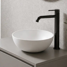 Modern bathroom with a floating vanity, round mirror, and plant.