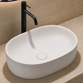 Bathroom sink with black faucet, towel, and plant on beige countertop