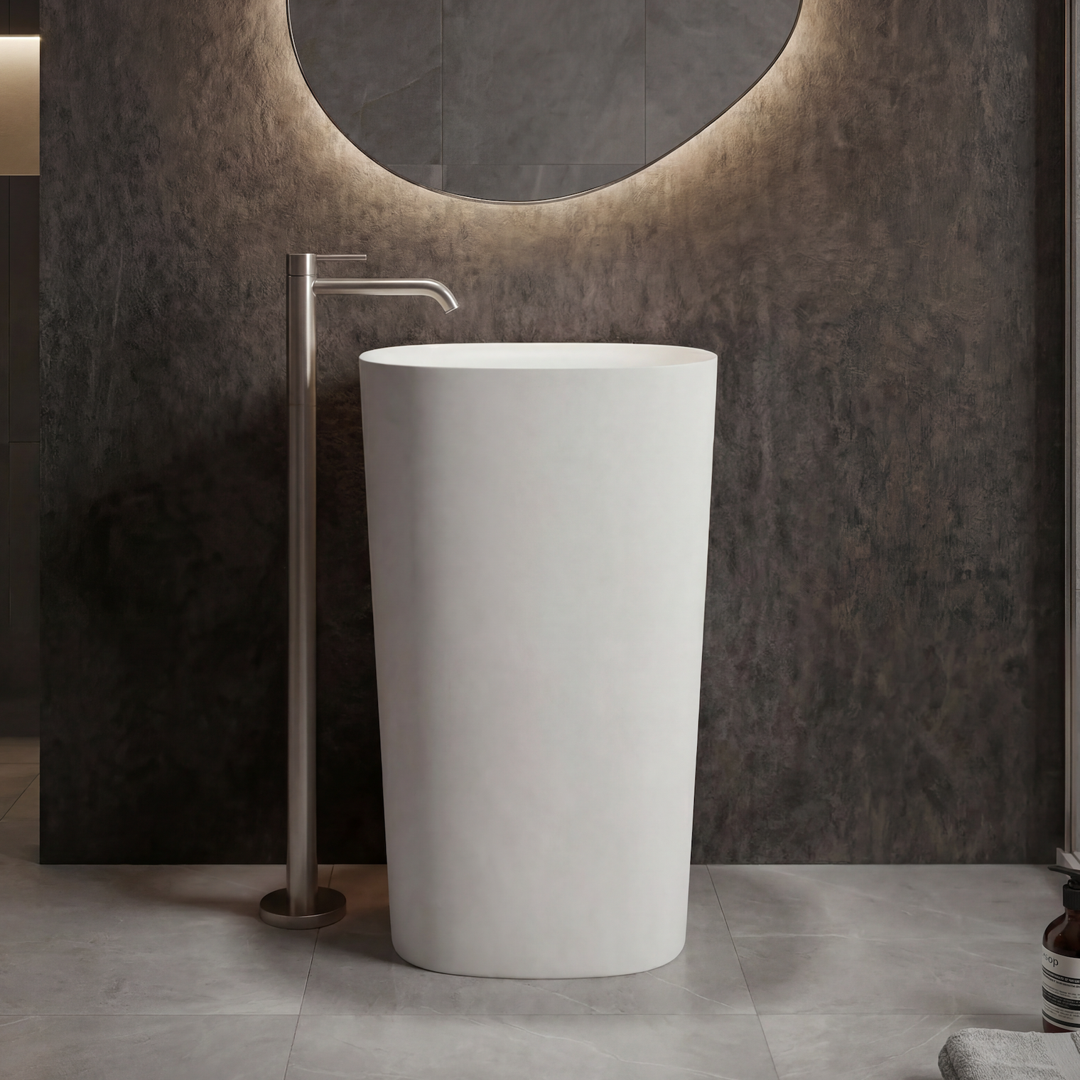 White freestanding sink in a modern bathroom setting with a circular mirror and neutral color palette.