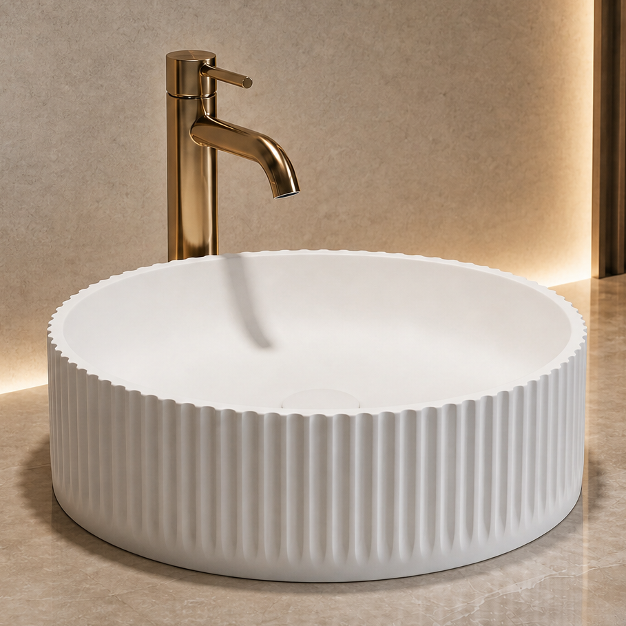 White ribbed solid surfaces sink on a marble countertop with a gold faucet