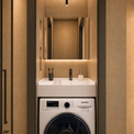 A modern bathroom setup featuring a Samsung washing machine integrated beneath a white double-sink vanity with a large mirror and warm ambient lighting.