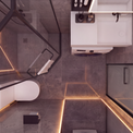 Modern bathroom interior with gray stone-look tiles, warm LED strip lighting, a white toilet, a white vanity unit, and a glass shower screen with black framing.