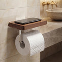 Wooden shelf with a smartphone and toilet paper holder mounted on a tiled bathroom wall.