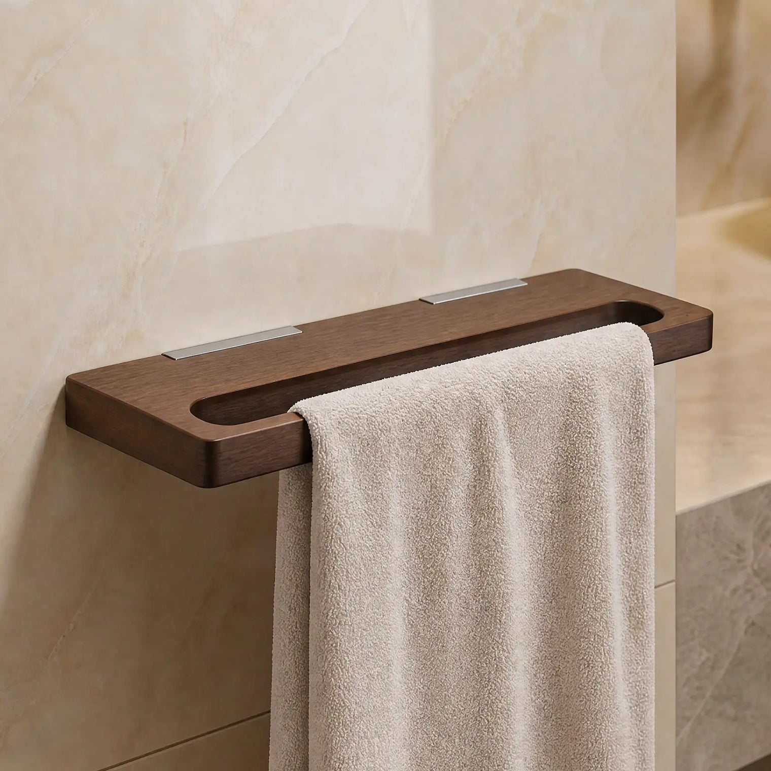 Towel hanging on a wooden towel rack in a bathroom with marble walls and a sink.