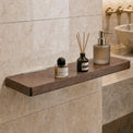 Bathroom counter with a wooden shelf holding skincare products against a tiled wall.