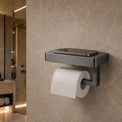 Modern black toilet paper holder with a roll of toilet paper on a beige tiled bathroom wall.