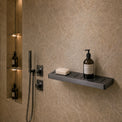 Modern bathroom with shower setup and toiletries on a shelf.