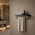 Bathroom interior with a shelf holding towels and toiletries against a tiled wall.