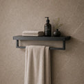 Bathroom interior with a shelf holding towels and toiletries against a tiled wall.