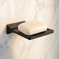 Black soap dish with a bar of soap on a marble wall