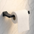 Roll of toilet paper on a black wall-mounted holder against a marble wall.