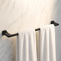 Black towel rack with white towels on a marble wall
