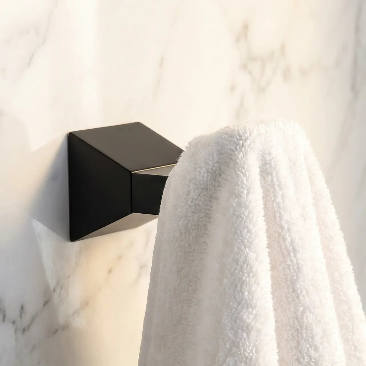 Black wall-mounted light fixture on a marble wall with a white towel draped over it.