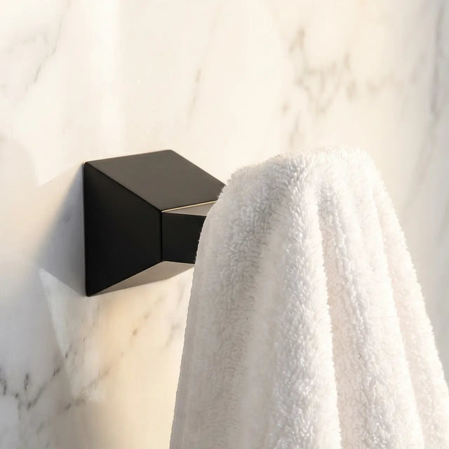 Black wall-mounted light fixture on a marble wall with a white towel draped over it.