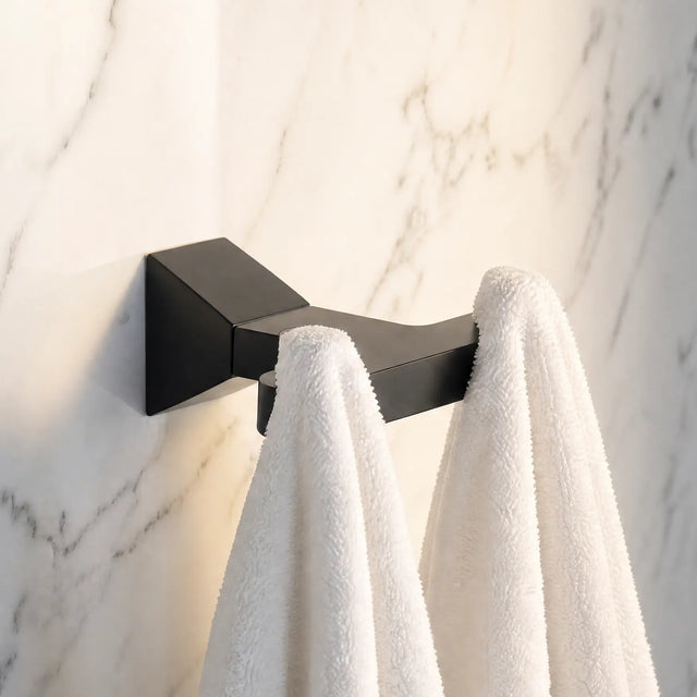 Black towel hook with white towels on a marble wall